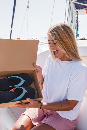 photo of a woman opening a shoebox with sandals inside, eco-friendly sandals, shoes, and slippers, Freewatersoes, Freewaters